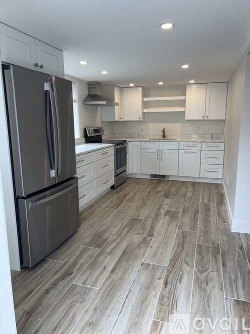 A modern kitchen with a refrigerator, sink, and cabinets.