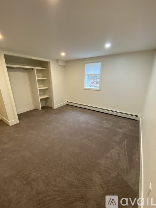 A room with a carpeted floor and a window with a view of a cityscape.