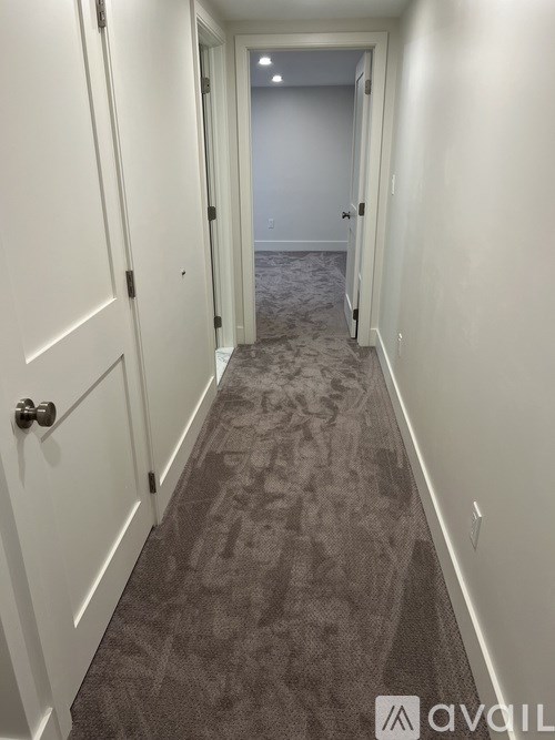 A hallway with a carpeted floor and white walls.