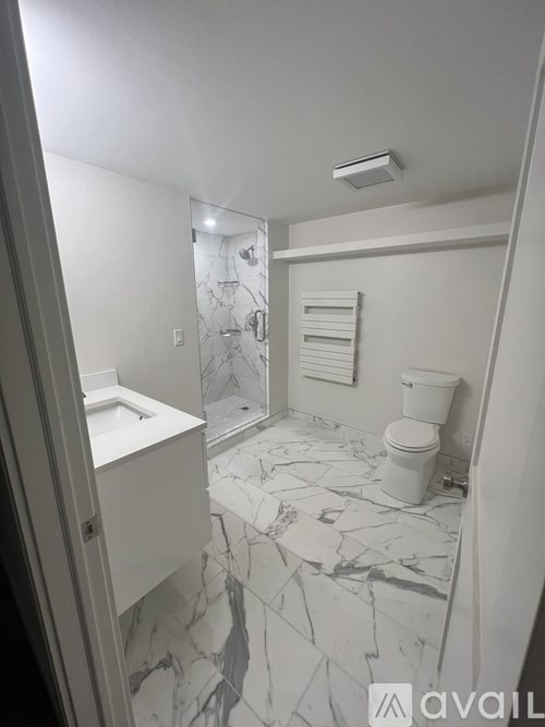 A bathroom with a marble floor and white fixtures.