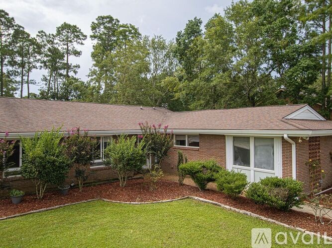 A house with a brown roof and a white door is surrounded by a garden.