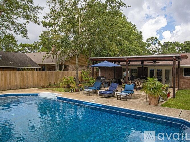 A pool with a blue umbrella and chairs in front of a house.