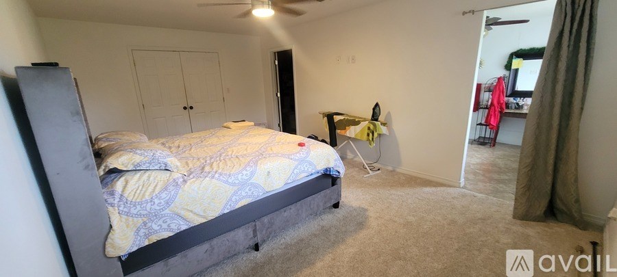 A bedroom with a bed, dresser, and a ceiling fan.
