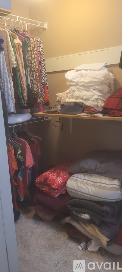 A messy room with clothes and a bed.