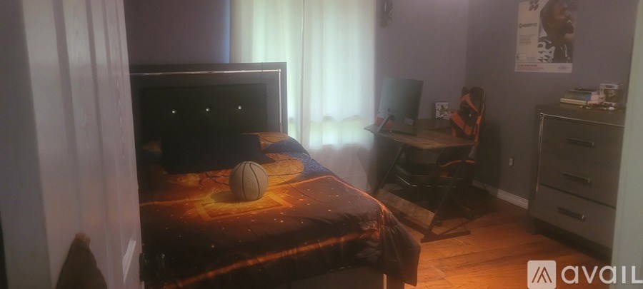 A bedroom with a bed, desk, and a television.