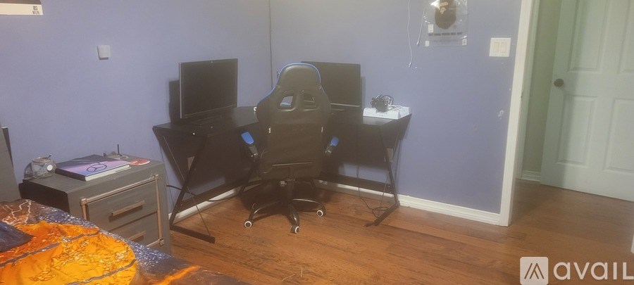 A room with a desk, computer, and chair.