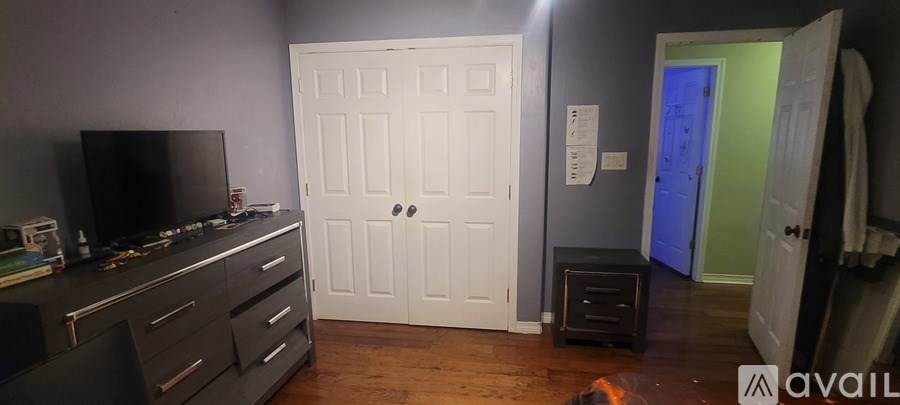 A room with a white door and a flat screen TV on a cabinet.
