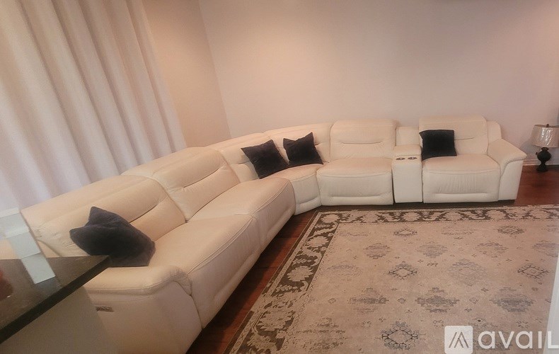A white sectional sofa with a glass table in front of it.