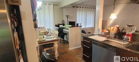 A kitchen with a refrigerator, sink, and a dining table with chairs.