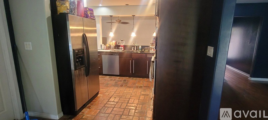 A kitchen with a refrigerator and a tile floor.