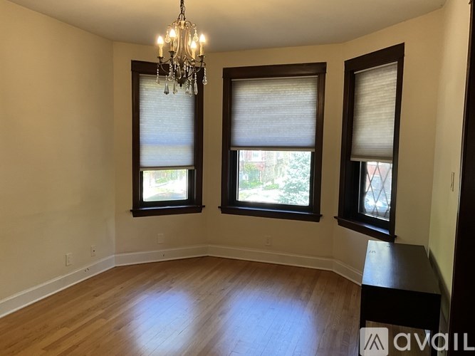 A room with wooden floors and three windows with blinds.
