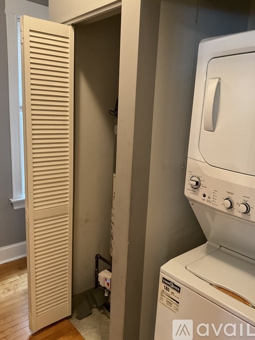 A white washing machine is in a small room with a door open.
