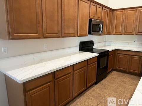 A kitchen with brown cabinets and a black stove top oven.