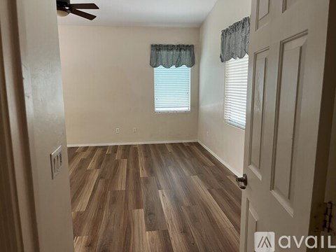 A room with wooden flooring and a window with blinds.