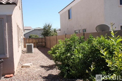 A backyard with a gravel path, a fence, and a bush.