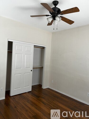 A room with a white door and a ceiling fan.