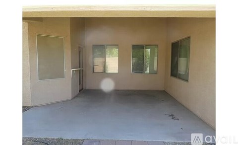 A concrete patio area with a door and windows.