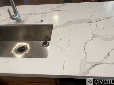 A close up of a sink with a metallic finish and a marble countertop.