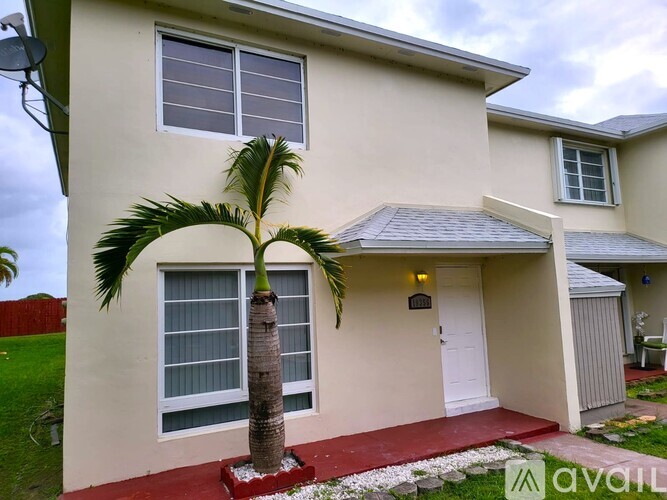 A house with a red carpet and a palm tree in front.