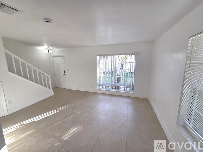 A spacious room with tiled flooring and a ceiling fan.