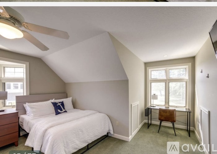 A bedroom with a bed, desk, and window.