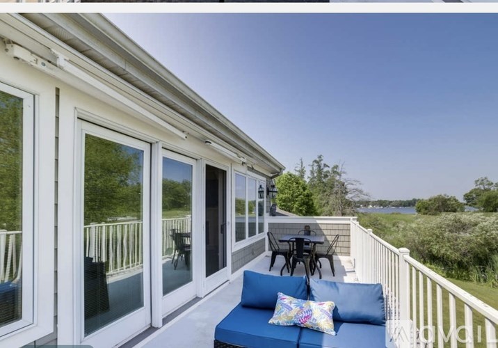 A white house with a blue couch and a table on the balcony.