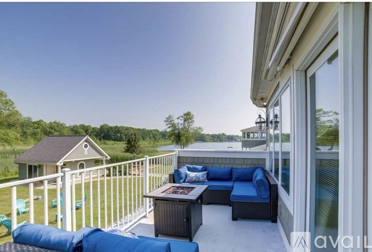 A balcony with a white railing, blue cushions, and a table with a magazine on it.