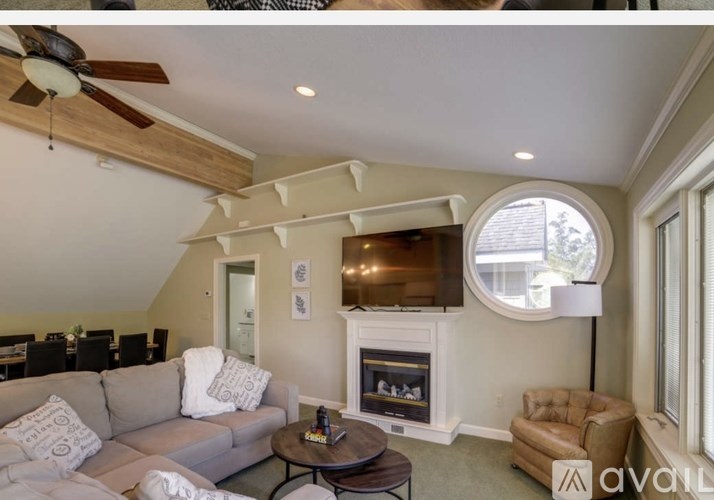 A living room with a grey couch, a fireplace, and a ceiling fan.