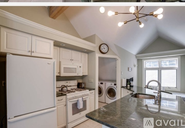 A kitchen with a white refrigerator, microwave, and oven, and a black granite countertop.