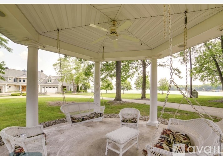A white gazebo with chairs and a swing set in the middle.