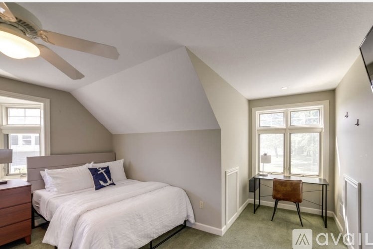 A bedroom with a bed, desk, and chair.