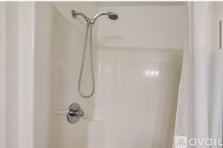 A white bathroom with a shower curtain and a shower head.