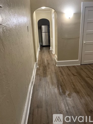 A hallway with a white door and a trash can.