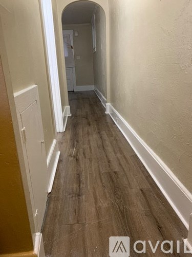 A hallway with wooden floors and white walls.