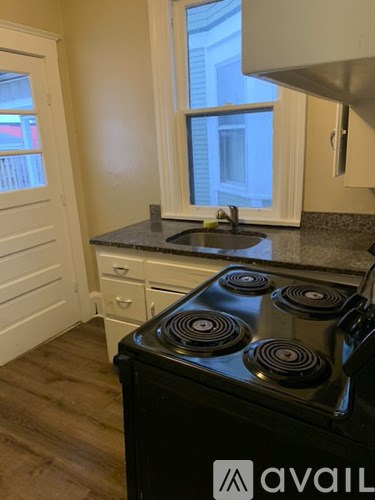 A black stove top oven in a kitchen with a window above it.