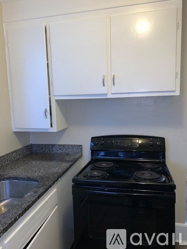A black stove in a kitchen with white cabinets.