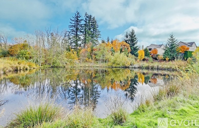 A serene landscape with a lake, trees, and houses.