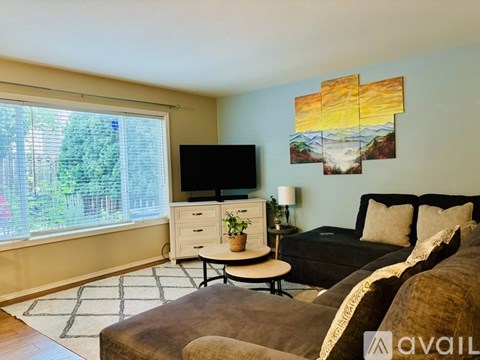A living room with a couch, a television, a plant, and a painting on the wall.