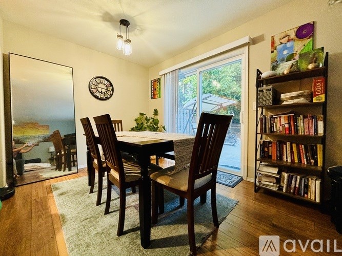 A dining room with a table and chairs and a bookshelf.