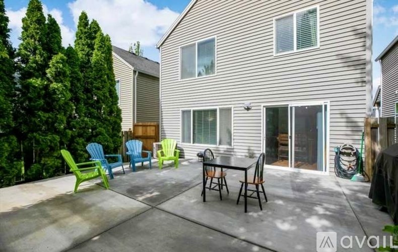 A patio with a table and chairs is in front of a house.
