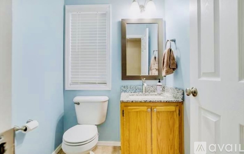 A bathroom with a toilet, sink, and mirror.