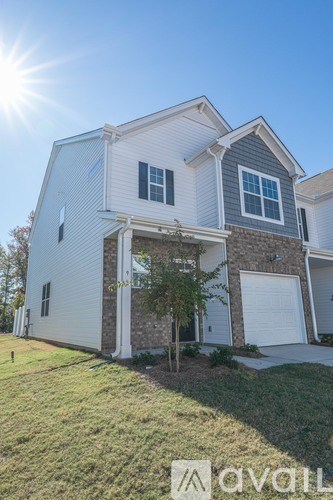 A two-story house with a garage is bathed in sunlight.