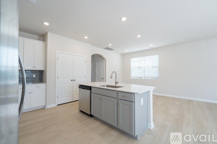 A modern kitchen with a refrigerator on the left and a sink in the middle.