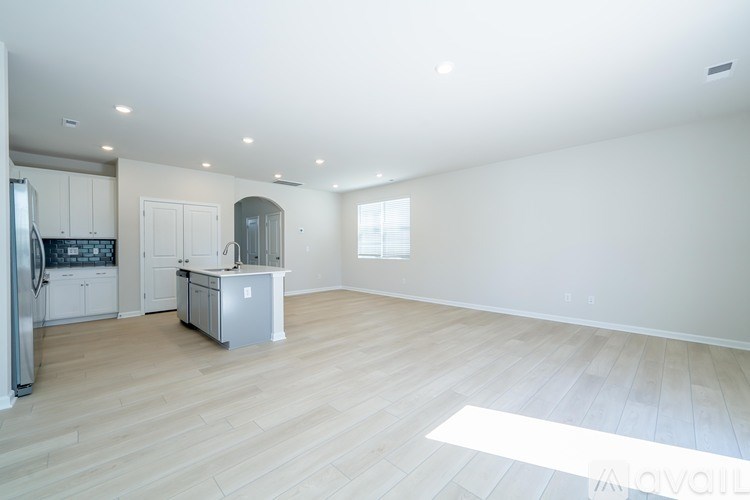 A spacious kitchen with light wood flooring and white walls.