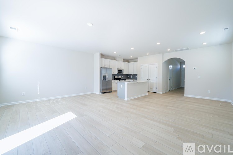 A spacious kitchen with white cabinets and a wooden floor.