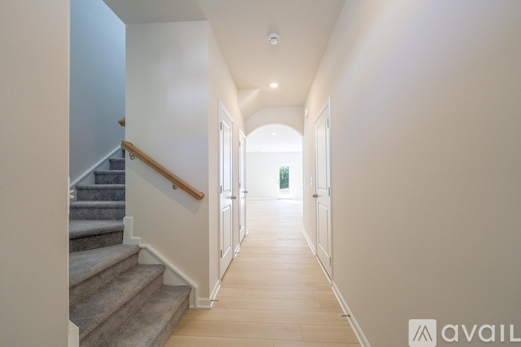 A long hallway with a staircase on the left and a door at the end.