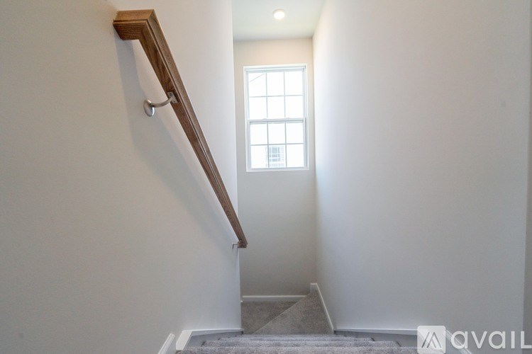 A staircase with a wooden handrail leads up to a small window.