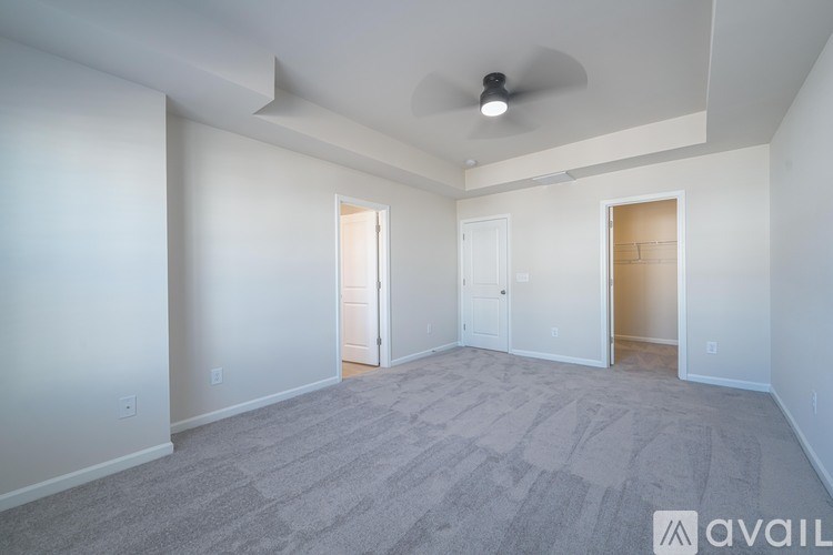 A spacious room with a carpeted floor and a ceiling fan.