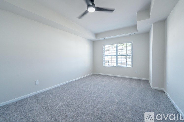 A room with a ceiling fan and a window with blinds.