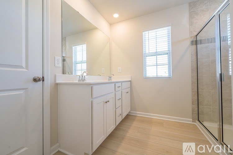 A bathroom with a white door, sink, and cabinets.